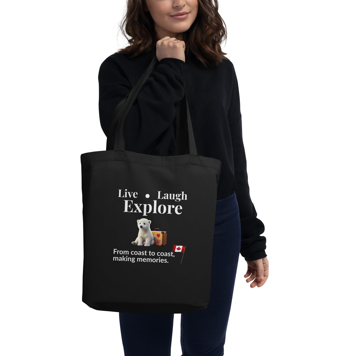 Woman holding a black eco tote bag with text, Live Laugh Explore, and a polar bear graphic.
