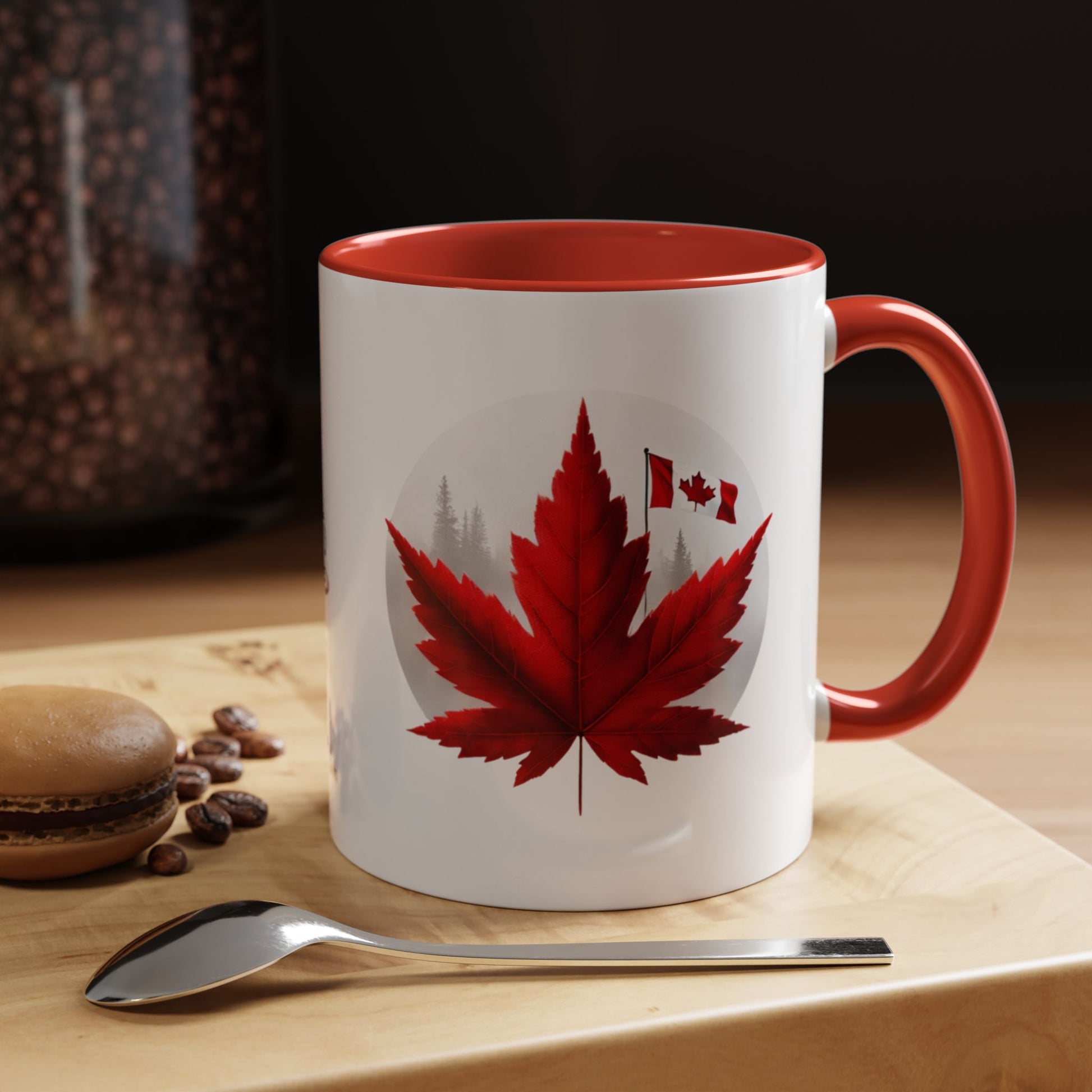White mug with red interior and handle featuring a red maple leaf design on a wooden surface with coffee beans and a spoon.