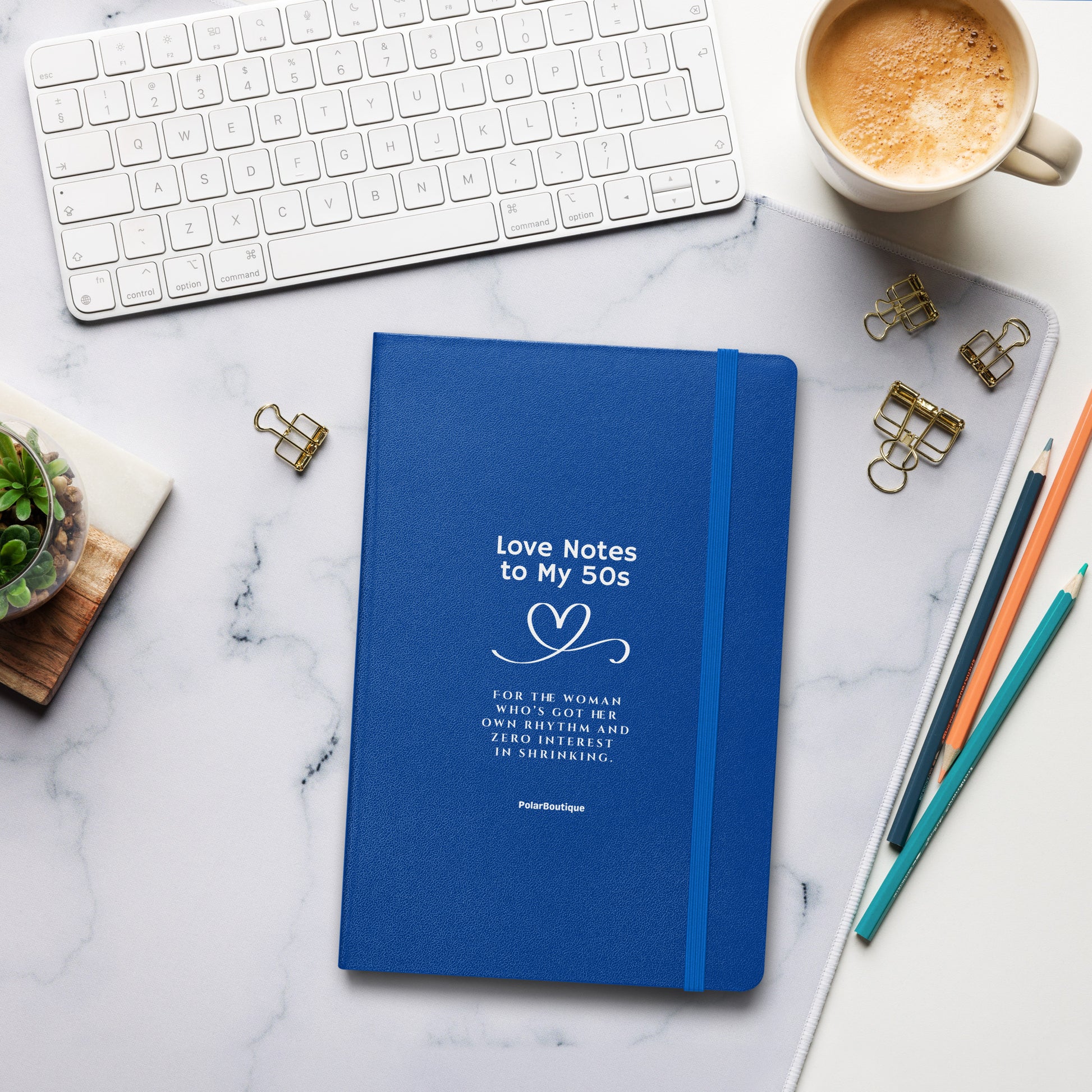 Love Notes to my 50s - Blue notebook with text on a marble desk with office supplies