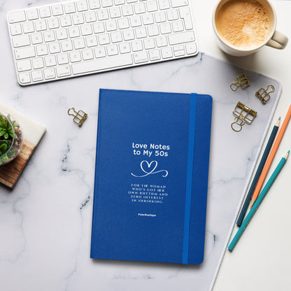Love Notes to my 50s - Blue notebook with text on a marble desk with office supplies