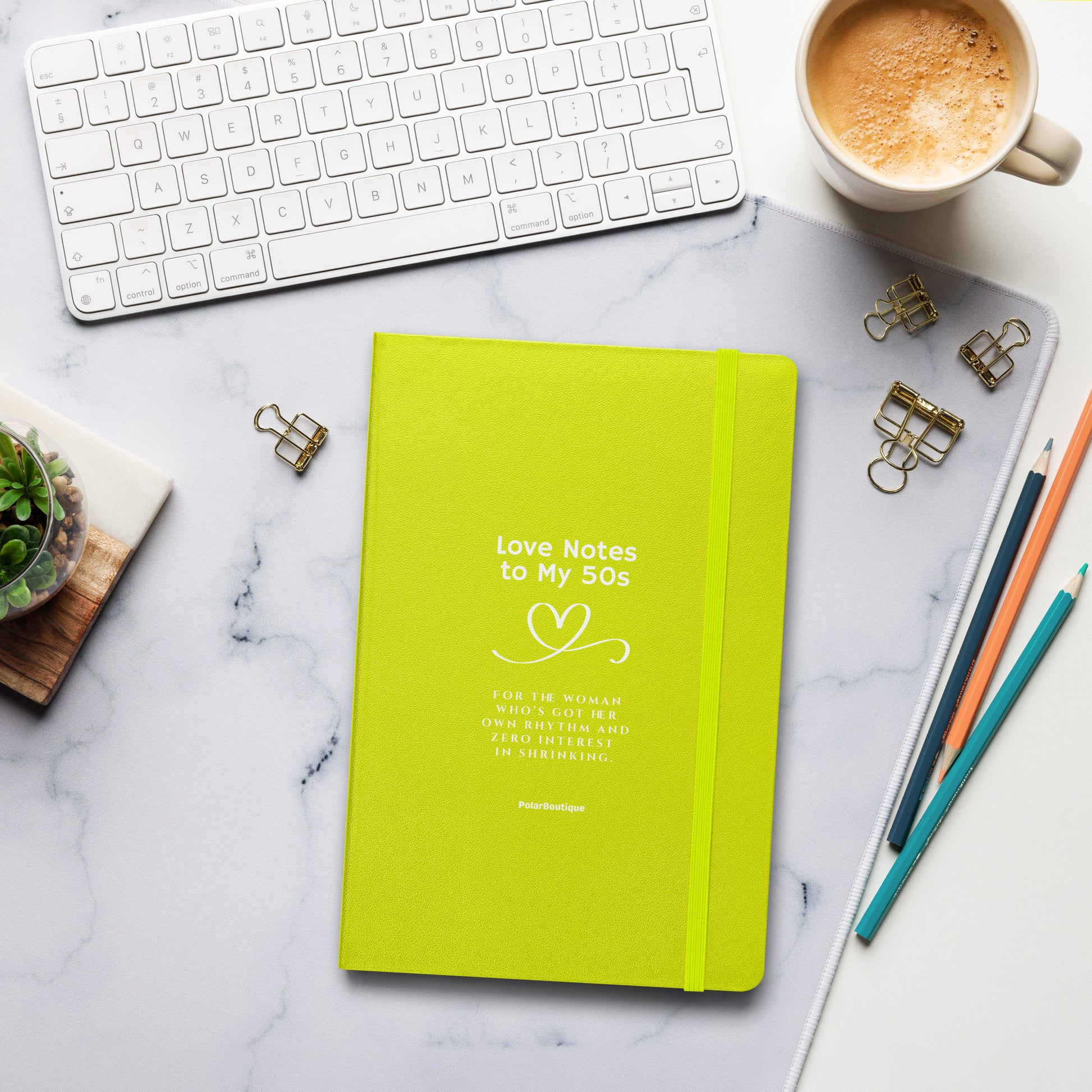 Green notebook titled 'Love Notes to My 50s' on a marble desk with office supplies.