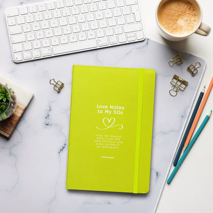 Green notebook titled 'Love Notes to My 50s' on a marble desk with office supplies.