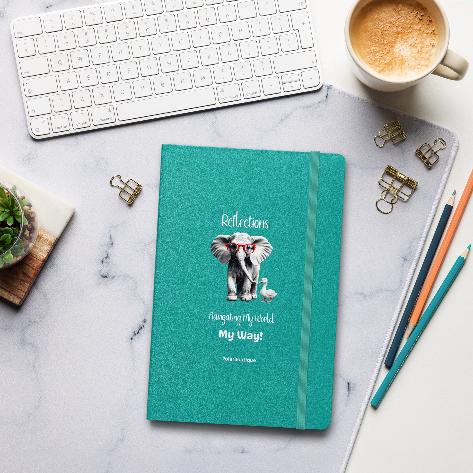Teal notebook with elephant illustration on a marble desk with office supplies